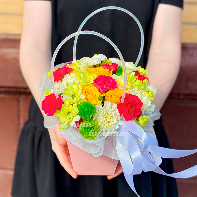 Яркие гвоздики и хризантемы в коробке (в руках флориста)